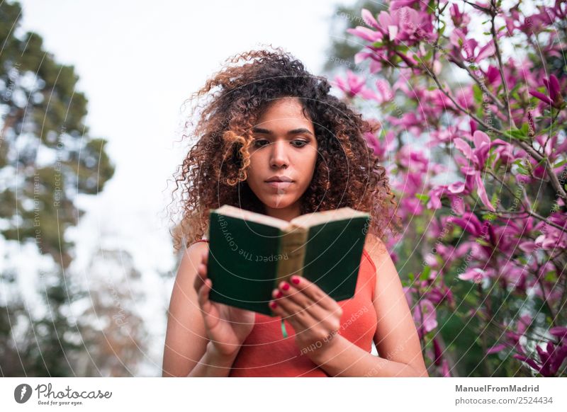 Afrofrau beim Lesen eines Buches im Freien Lifestyle Glück schön Freizeit & Hobby lesen Sommer Garten Schule lernen Mensch Frau Erwachsene Natur Baum Blume Gras