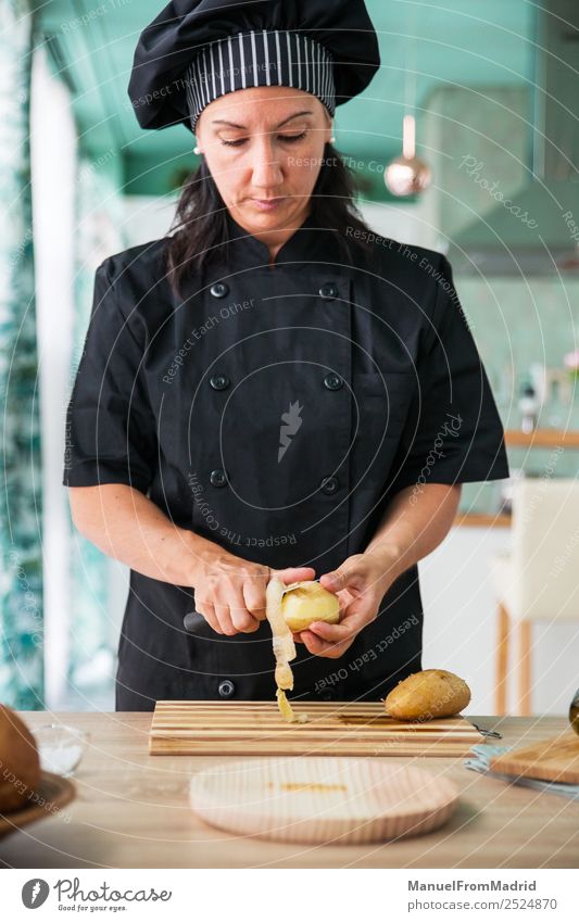 Köchin beim Schälen einer Kartoffel Ernährung Teller Tisch Küche Mensch Frau Erwachsene Hand Holz modern Konzentration Küchenchef Koch angeblättert Kartoffeln