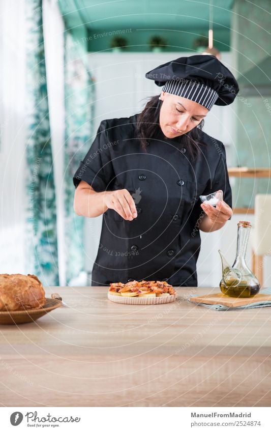 Köchin, die ein Gericht würzt. Kräuter & Gewürze Ernährung Teller Tisch Küche Mensch Frau Erwachsene Hand Hut Holz modern Küchenchef Koch Hinzufügen Salz