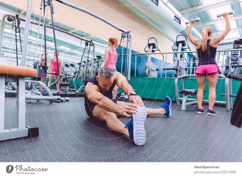 Männer, die sich dehnen und Frauen, die Kurzhantel-Übungen im Fitnessstudio machen. Lifestyle Glück schön Körper Freizeit & Hobby Club Disco Sport Mensch