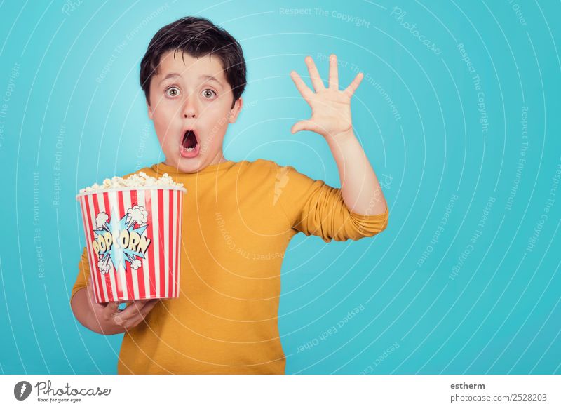 überraschtes Kind mit Popcorn auf blauem Hintergrund Lebensmittel Essen Fasten Lifestyle Freude Freizeit & Hobby Entertainment Mensch maskulin Kleinkind