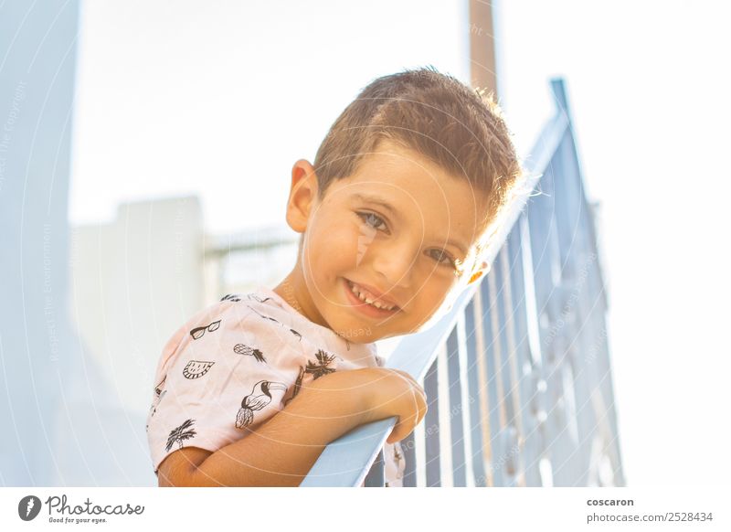 Kleiner Junge, der sich auf ein Geländer in einem weiß-blauen Dorf stützt. Lifestyle Freude Glück schön Gesicht Ferien & Urlaub & Reisen Tourismus Sommer