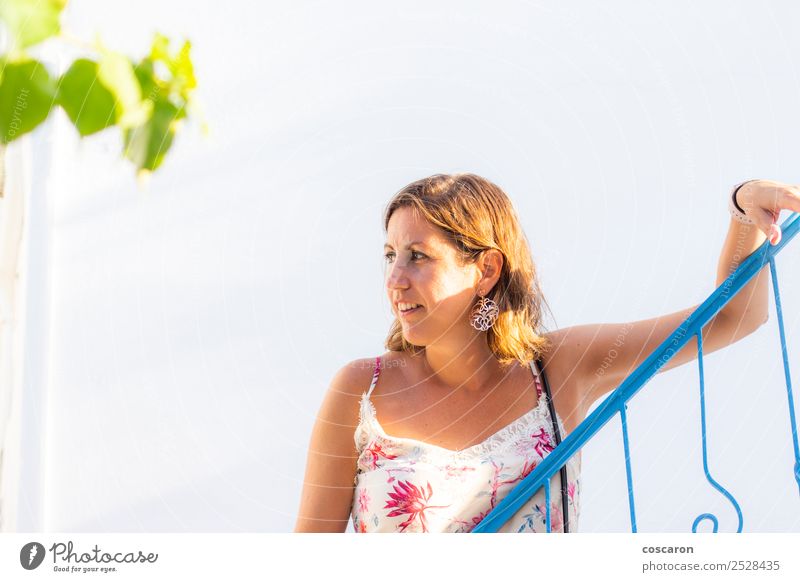 Mittelalterliche Frau, die sich auf ein blaues Geländer in einem griechischen Dorf stützt. Stil schön Haare & Frisuren Ferien & Urlaub & Reisen Tourismus