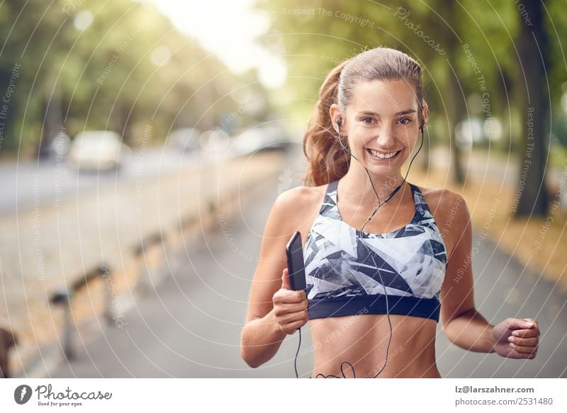 Junge sportliche Frau beim Joggen Lifestyle Sommer Musik Sport PDA Erwachsene Wärme Park Straße Fitness Lächeln rennen Gesundheit üben jung Training Motivation