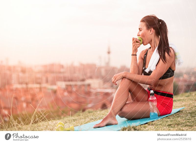 athletische Frau beim Essen eines Apfels Frucht Lifestyle schön Körper Wellness Sommer Sport Joggen Mensch Erwachsene Natur Park Fitness sitzen grün Athlet jung