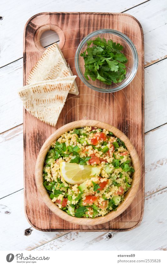 Tabbouleh-Salat mit Couscous auf weißem Holz. Draufsicht. Tisch Salatbeilage Gemüse Tomate Gurke Salatgurke Petersilie Minze Vegane Ernährung