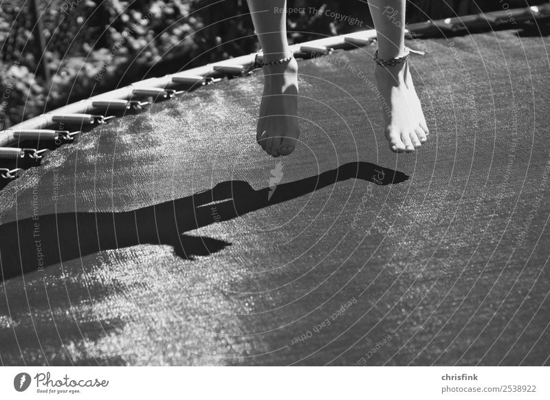 Mädchen auf Trampolin sw Garten Sport Mensch Kind Fuß 1 springen grau Freude Schatten Gartentrampolin Salto Schwarzweißfoto Außenaufnahme Tag