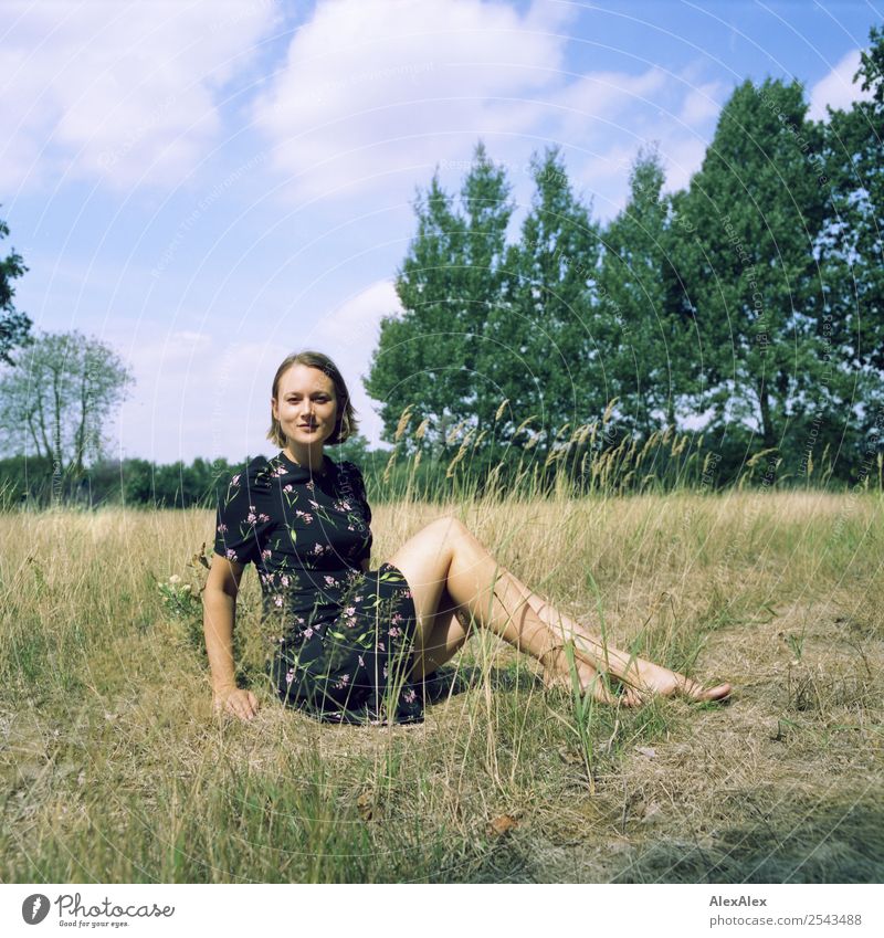 analoges Mittelformat Portrait einer jungen Frau die barfuß im Sommerkleid auf einem Feld in der Heide sitzt Freude schön Wellness harmonisch Wohlgefühl