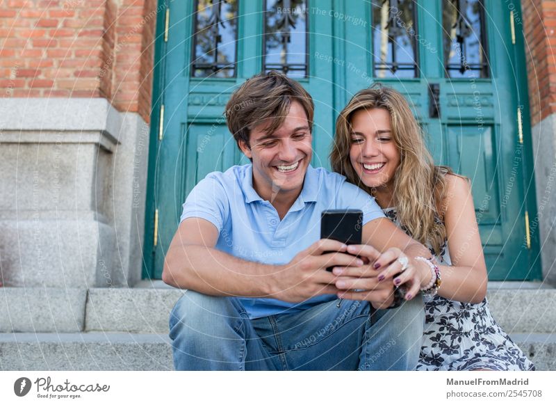 junges Paar am Telefon Lifestyle Glück schön Leben Freizeit & Hobby PDA Technik & Technologie Frau Erwachsene Mann sprechen Lächeln lachen lesen Liebe sitzen