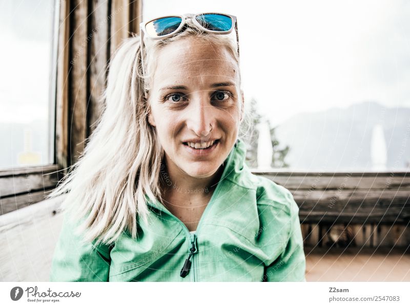Junge Frau in einer Berghütte Lifestyle wandern Umwelt Natur Landschaft Sommer Schönes Wetter Alpen Berge u. Gebirge Trainingsjacke Sonnenbrille blond Zopf