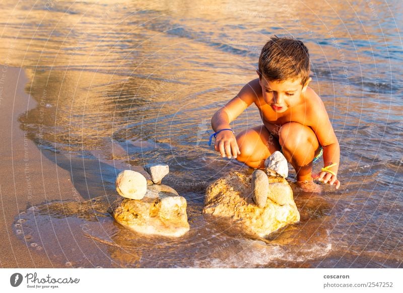 Kleines Kind, das am Strand mit Steinen baut. Lifestyle Freude Glück Freizeit & Hobby Spielen Ferien & Urlaub & Reisen Tourismus Sommer Sonne Meer Mensch