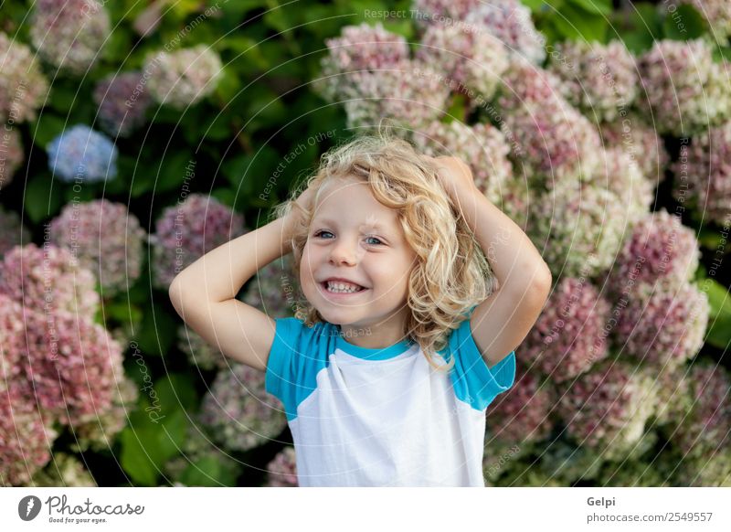 Süßes kleines Kind mit langen Haaren im Garten Glück schön Gesicht Sommer Mensch Baby Junge Mann Erwachsene Kindheit Hand Umwelt Natur Pflanze Blume blond