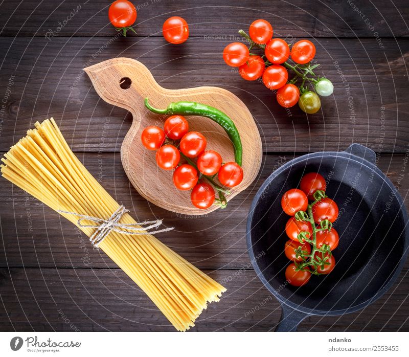 rohe Spaghetti und rote Kirschtomaten Gemüse Teigwaren Backwaren Abendessen Pfanne Tisch Holz frisch gelb weiß Spätzle Lebensmittel Hintergrund Tomate