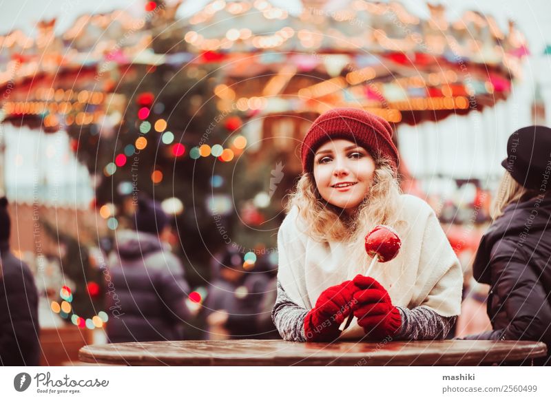 junges glückliches Mädchen isst Karamellapfel, Spaziergang in der Weihnachtsstadt kaufen Glück Winter Dekoration & Verzierung Silvester u. Neujahr Frau