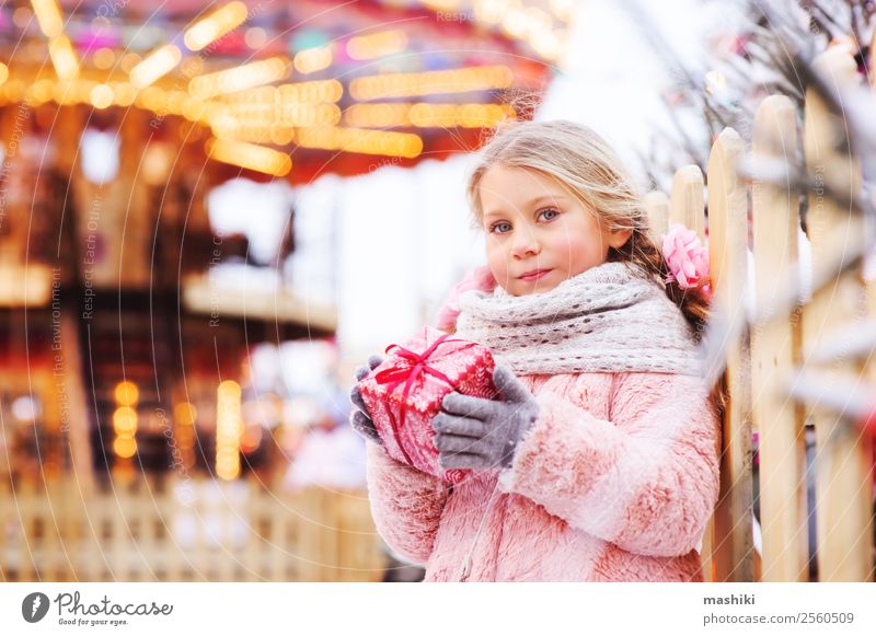 glückliches Kind Mädchen hält Weihnachtsgeschenk im Freien auf dem Spaziergang kaufen Winter Schnee Dekoration & Verzierung Silvester u. Neujahr Kindheit Mode
