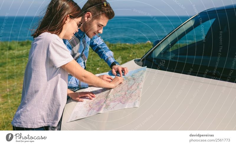 Ein Paar schaut sich eine Karte an, die sich auf das Auto stützt. schön Ferien & Urlaub & Reisen Ausflug Abenteuer Meer Mensch Frau Erwachsene Mann Gras Wiese