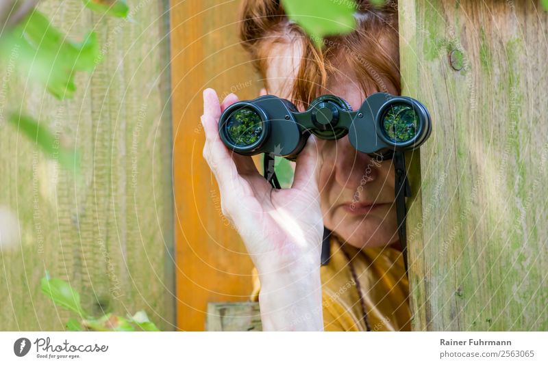 eine Frau beobachtet durch ein Fernglas Mensch feminin Erwachsene Kopf Hand 1 Natur Garten rothaarig beobachten Neugier Interesse Rache "Gartenzaun Zaun Spion