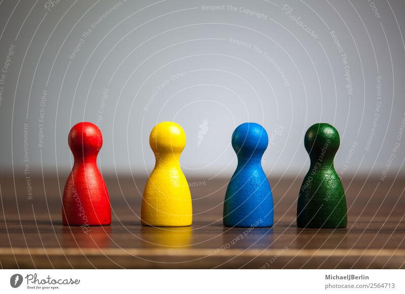 Vier Spielfiguren auf Tisch in diversen Farben Spielen Business blau mehrfarbig gelb grün rot Symbole & Metaphern Vielfältig Verschiedenheit different