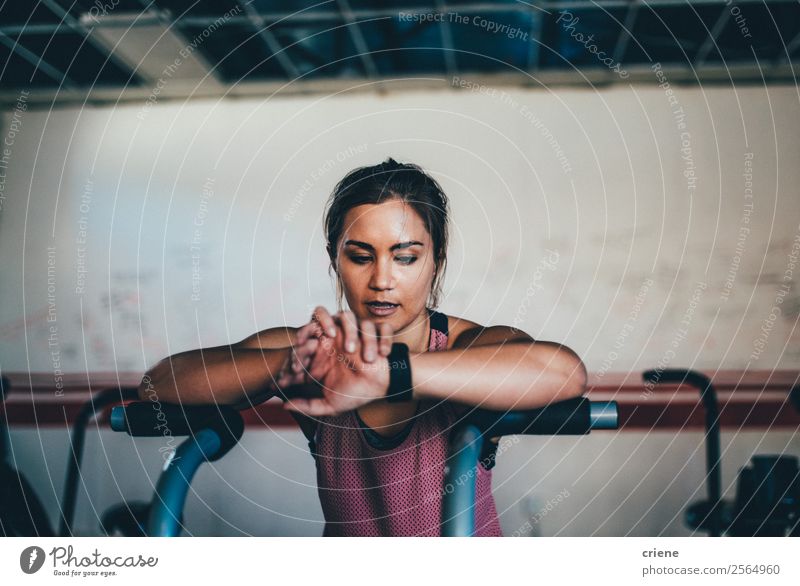 Frau, die Smartwatch überprüft, während sie im Fitnessstudio trainiert. Lifestyle schön Körper Uhr Sport Technik & Technologie Mensch Erwachsene beobachten klug