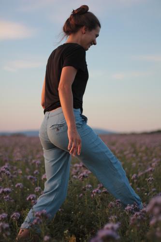Wiese Blumen Frau Himmel Erwachsene 1 Mensch 30-45 Jahre Natur Landschaft Sonnenlicht Sommer Gras Feld T-Shirt Jeanshose brünett Zopf entdecken Erholung Lächeln