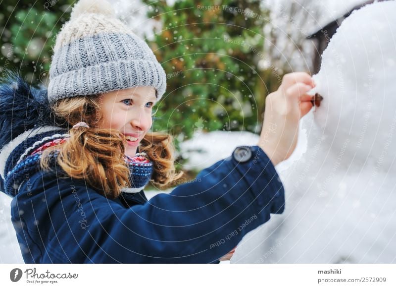 glückliches Kind Mädchen macht Schneemann an Weihnachten Freude Freizeit & Hobby Spielen Ferien & Urlaub & Reisen Winter Garten Natur Wetter Park Bekleidung