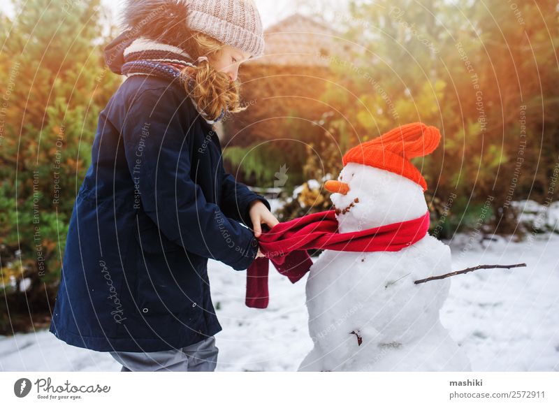 glückliches Kind Mädchen macht Schnee Mann Freude Freizeit & Hobby Spielen Ferien & Urlaub & Reisen Winter Garten Natur Wetter Park Bekleidung machen Schneemann