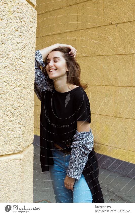 Lifestyle-Porträt einer glücklichen jungen erwachsenen Frau, die lacht. Glück lachen Wand Stil stehen Blick Behaarung 1 Model lässig Freizeitbekleidung weiß