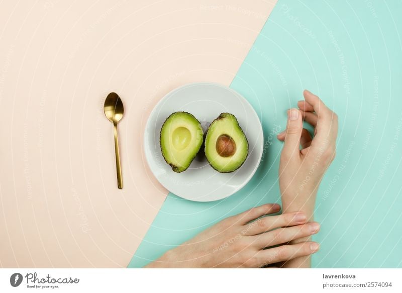 Flachlegen mit geschnittener Avocado auf weißem Teller und Frauenhänden Löffel Vegetarische Ernährung Vegane Ernährung Frucht Essen flache Verlegung Zutaten