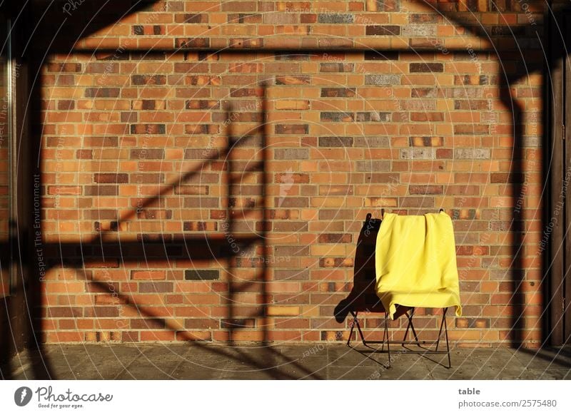 Stuhl mit Decke neben Schatten vom Baugerüst... Handwerk Baustelle Schönes Wetter Haus Bauwerk Gebäude Mauer Wand Fassade Terrasse Stein Metall Linie sitzen
