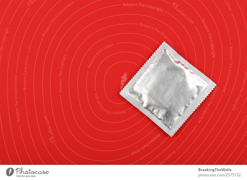 Nahaufnahme Kondom Silber Wickelpack über rotem Hintergrund Gesundheit Gesundheitswesen neu oben Sicherheit Schutz Verantwortung Vorsicht Kontrolle Metallfolie