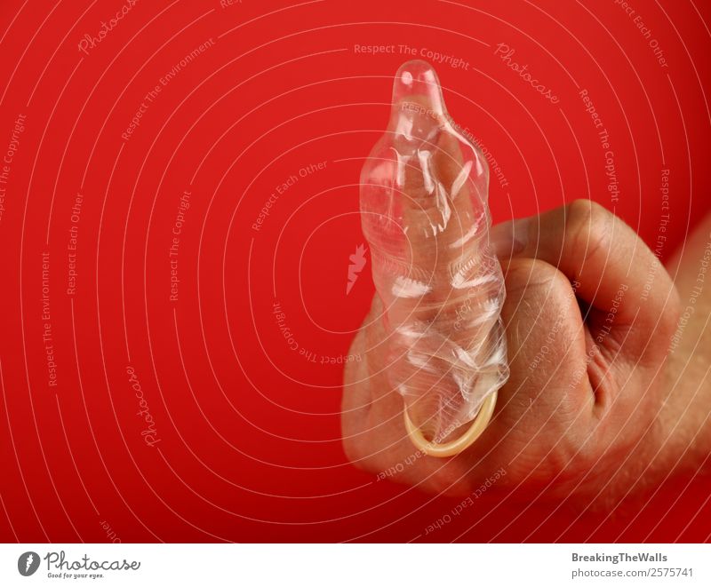 Nahaufnahme der Männerhand mit Kondom am Finger Gesundheit Gesundheitswesen Behandlung Medikament Mann Erwachsene Hand Aggression rebellisch Klischee rot Schutz