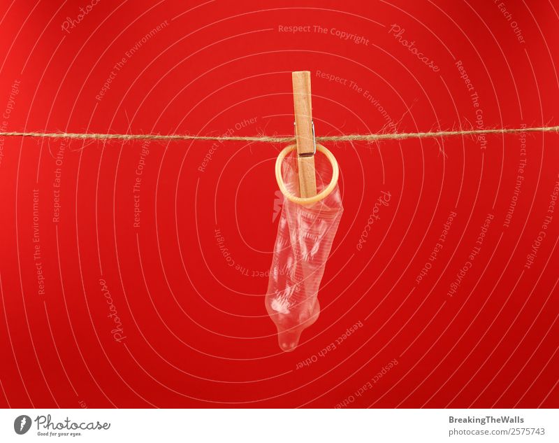 Nahaufnahme Kondom an der Waschlinie über rot hängend Gesundheit Gesundheitswesen Medikament Holz Linie Schnur Sicherheit Schutz Verantwortung Vorsicht Farbe