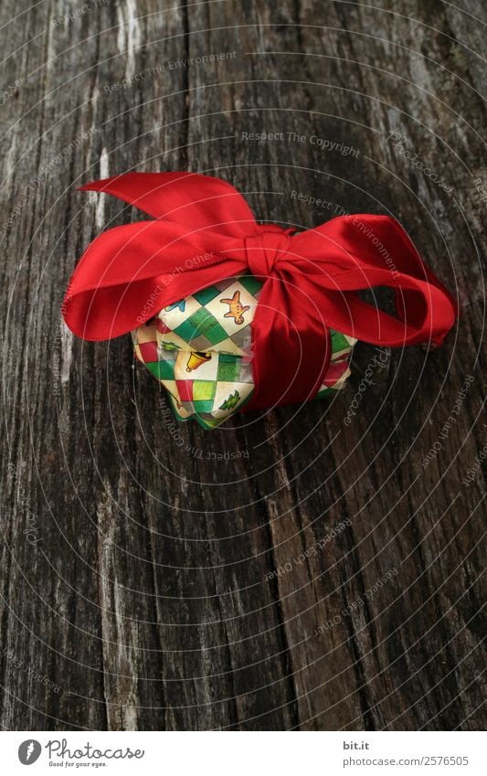bunte Weihnachtspäckchen verpackt mit Weihnachtspapier mit roter Schleife, auf rustikalem Holz. Weihnachtsgeschenke, liegen hübsch dekoriert mit Band auf Holztisch. Viele Weihnachtspäckchen mit Geschenkpapier mit Weihnachtsmotiv. Konzept Geschenke Advent.
