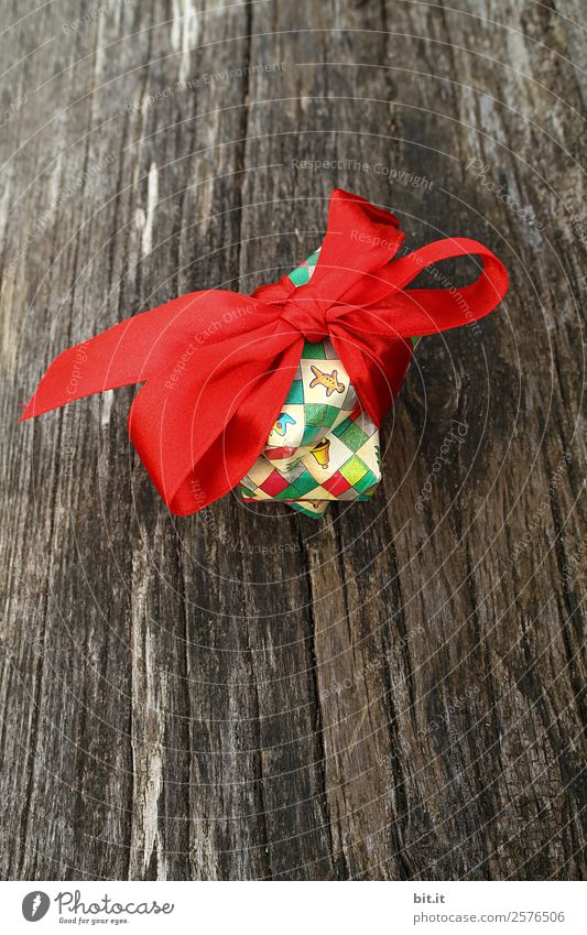 bunte Weihnachtspäckchen verpackt mit Weihnachtspapier mit roter Schleife, auf rustikalem Holz. Weihnachtsgeschenke, liegen hübsch dekoriert mit Band auf Holztisch. Viele Weihnachtspäckchen mit Geschenkpapier mit Weihnachtsmotiv. Konzept Geschenke Advent.