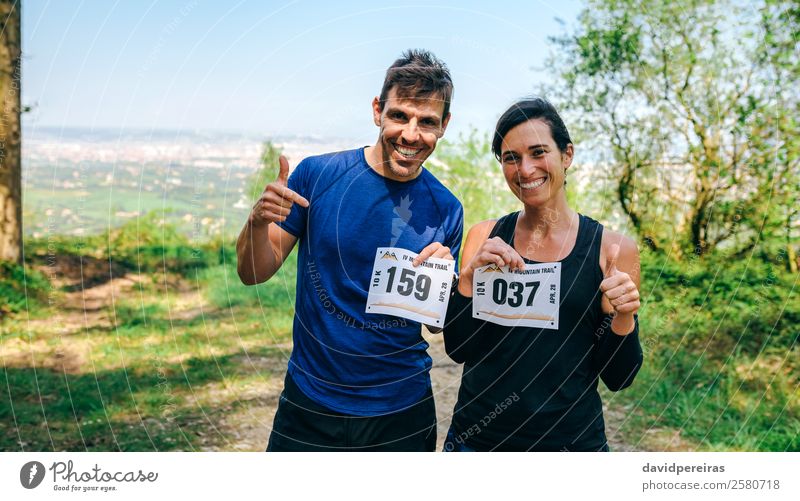 Mann und Frau zeigen ihre Trail-Rennnummer an. Lifestyle Glück Sport Erfolg Mensch Erwachsene Freundschaft Paar Natur Wald Wege & Pfade Lächeln stehen