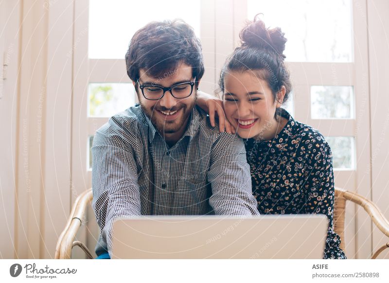 Attraktives Paar mit einem Laptop Freude Glück Computer Notebook Technik & Technologie Internet Frau Erwachsene Mann Vollbart Lächeln lachen Liebe sitzen