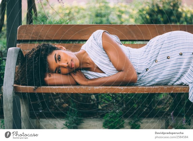 Schöne junge schwarze Frau, die sich auf einem Stuhl in einem Park niederlässt. Beautyfotografie Nahaufnahme Porträt multiethnisch Afrikanisch