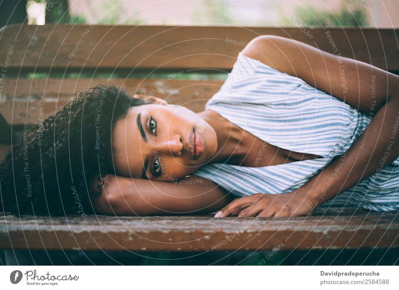 Schöne junge schwarze Frau, die sich auf einem Stuhl in einem Park niederlässt. Lifestyle Glück schön Erholung Sommer Garten Erwachsene Natur Kleid liegen
