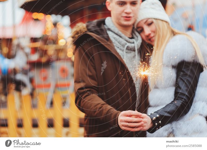 glückliches Paar mit Weihnachtsfeuerwerk, das in der Stadt spazieren geht. kaufen Freude Glück Ferien & Urlaub & Reisen Winter Dekoration & Verzierung