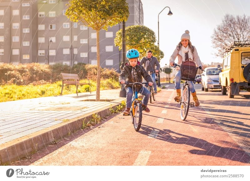 Glückliche Familie mit einem Kind, das Fahrräder durch die Stadt fährt. Lifestyle Erholung Freizeit & Hobby Ferien & Urlaub & Reisen Sonne Winter Sport Junge