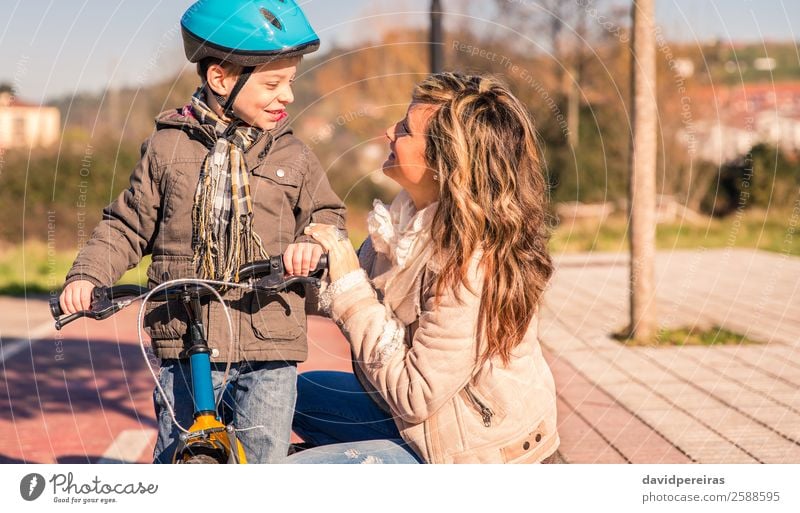 Glückliche junge Mutter mit ihrem Sohn, der über dem Fahrrad steht. Lifestyle Erholung Freizeit & Hobby Ferien & Urlaub & Reisen Sonne Winter Sport Kind Junge