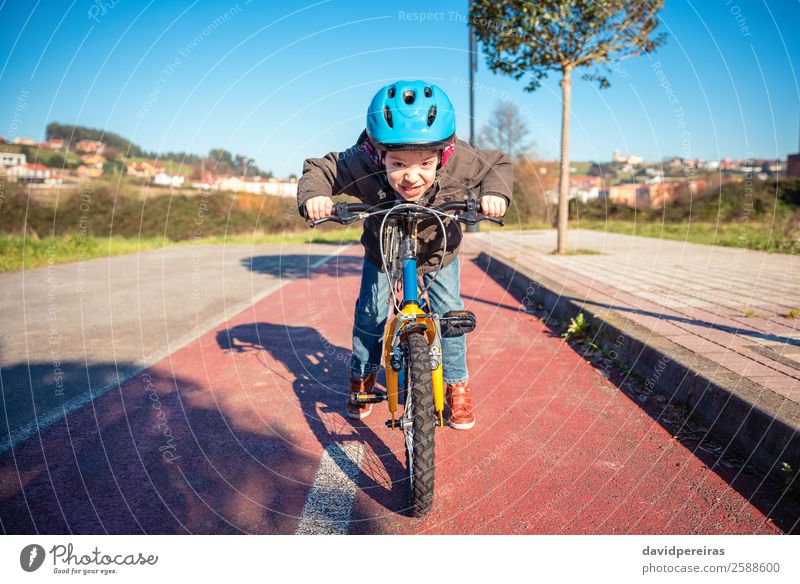 Frecher Junge mit trotziger Geste über Fahrrad auf einem Radweg Lifestyle Freude Glück Gesicht Freizeit & Hobby Spielen Sonne Winter Sport Fahrradfahren Kind