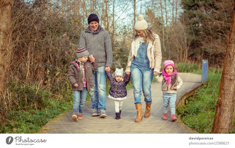 Glückliche Familie, die gemeinsam über einen Holzweg geht. Lifestyle Freude Freizeit & Hobby Winter Kind Junge Frau Erwachsene Mann Eltern Mutter Vater