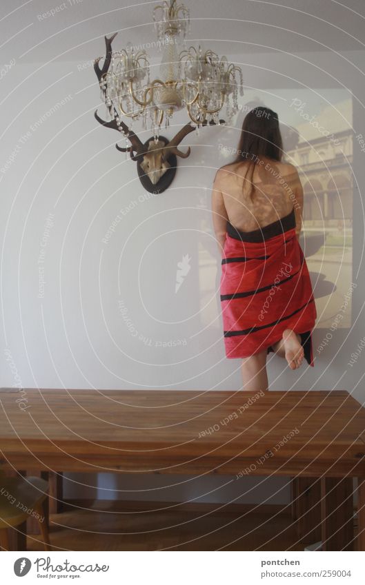 Rückansicht einer nackten Frau mit Handtuch bekleidet steht vor diaprojektion im Esszimmer hinter einem Holztisch Häusliches Leben Wohnung feminin Junge Frau
