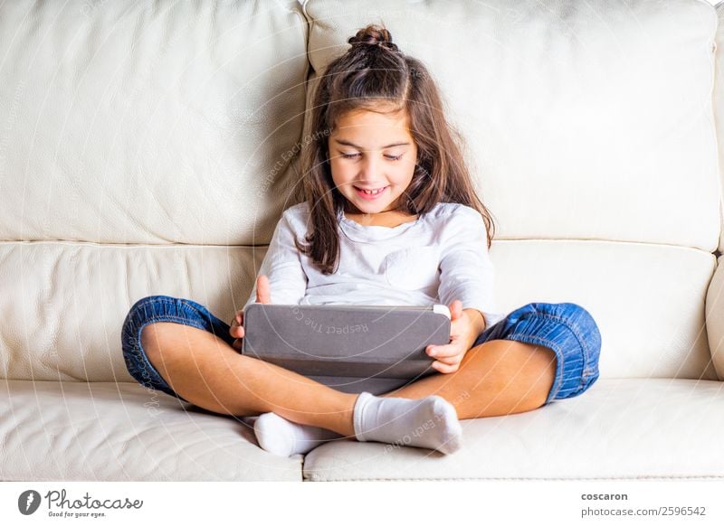 Kleines Mädchen mit einer Tablette zu Hause Lifestyle Glück schön Freizeit & Hobby Spielen Sofa Entertainment Bildung Kind lernen Funktelefon Computer Notebook