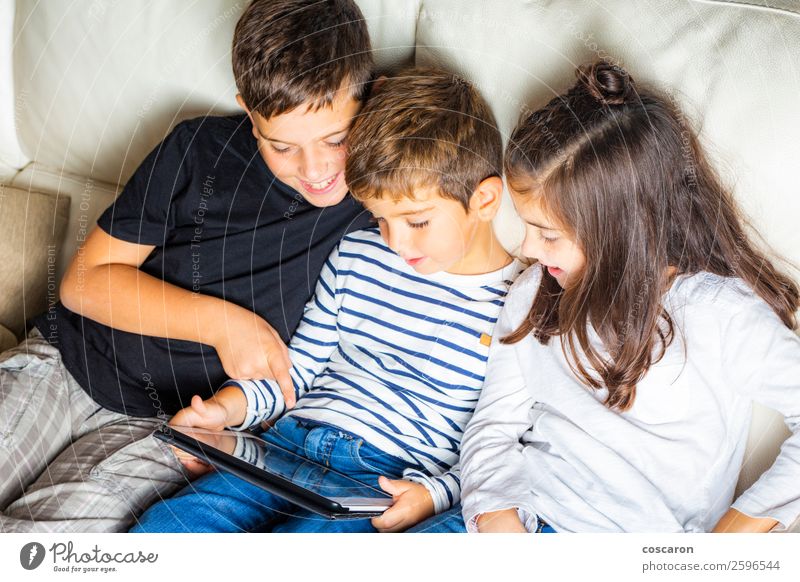 Drei Kinder benutzen zu Hause ein Tablett. Lifestyle Freude Glück schön Freizeit & Hobby Spielen lesen Sofa Funktelefon Spielkonsole Computer Notebook