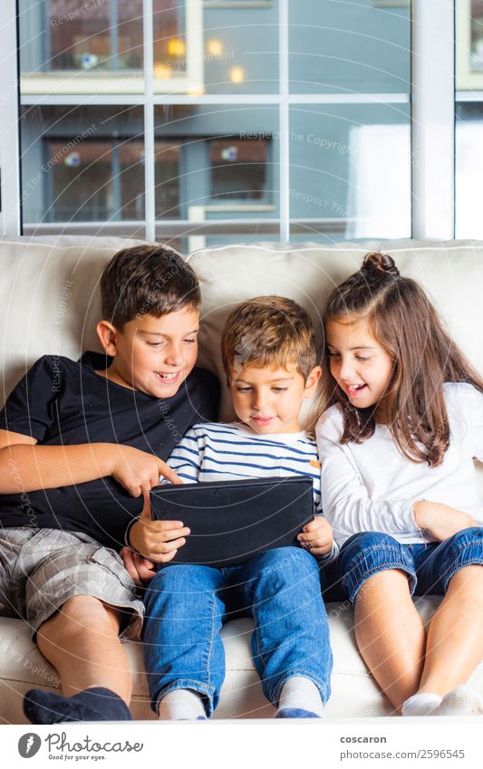 Drei Kinder benutzen zu Hause ein Tablett. Lifestyle Freude Glück schön Freizeit & Hobby Spielen Sofa Bildung lernen Schüler Handy Computer Notebook Bildschirm