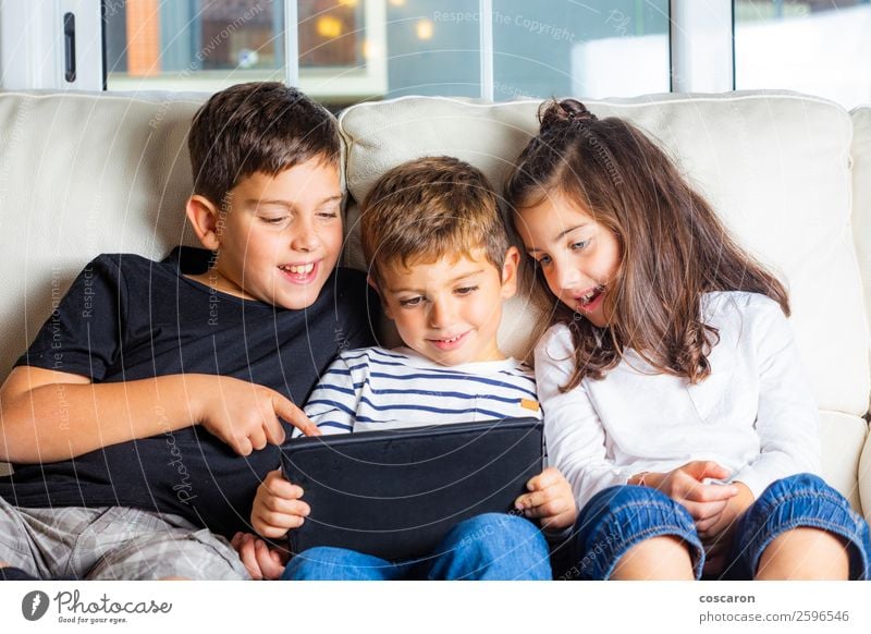 Drei Kinder benutzen zu Hause ein Tablett. Lifestyle Freude Glück schön Freizeit & Hobby Spielen Sofa Bildung lernen Funktelefon Computer Notebook Bildschirm