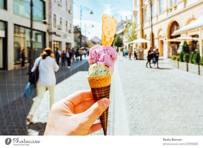 Mann hält grüne und rosa Eiscreme in der Hand. Lebensmittel Milcherzeugnisse Dessert Speiseeis Süßwaren Essen Fastfood Lifestyle Stil Freude