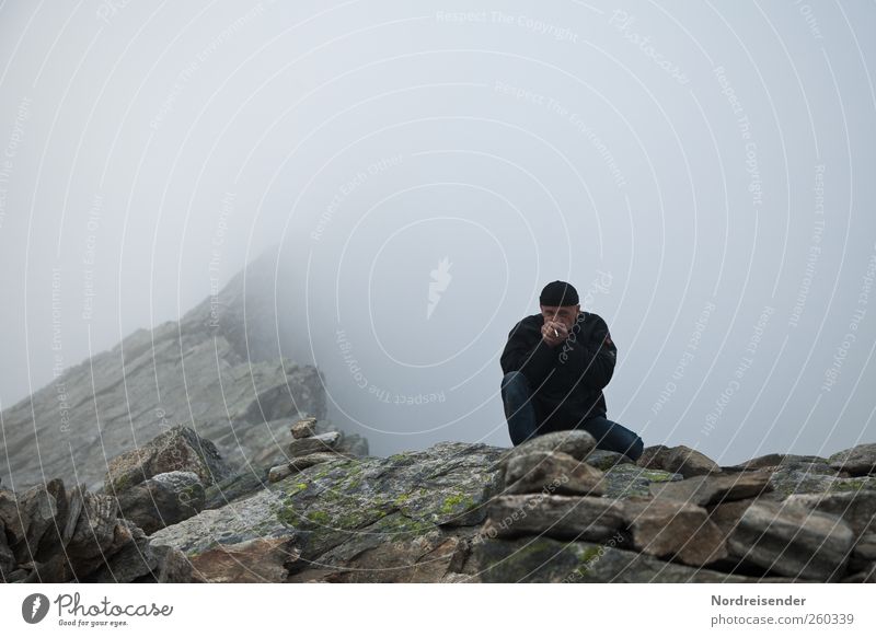 Mann auf einer Klippe im Hochgebirge Mensch Erwachsene 1 Natur Urelemente schlechtes Wetter Felsen Berge u. Gebirge Gipfel Schlucht Mütze frieren wandern